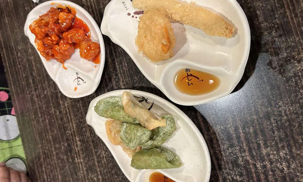 Three small white ceramic plates holding sweet sour chicken, tempura veggies and colorful fried dumplings with dipping sauces at Sushi & king seafood , a Sushi Restaurant in Commack